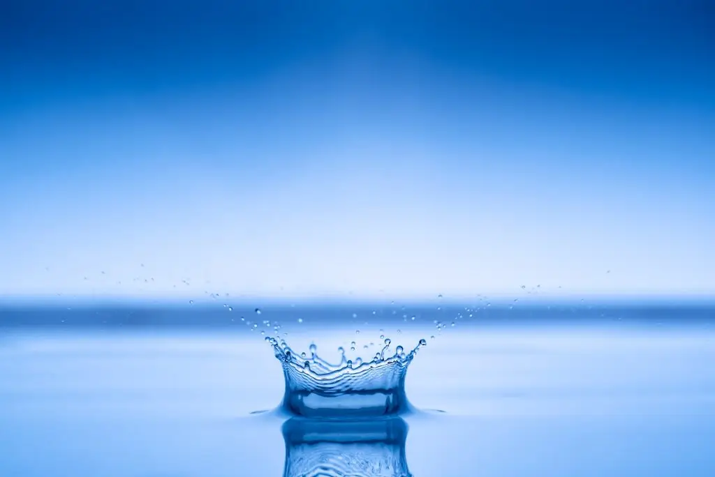 Water drop splashing into blue water surface