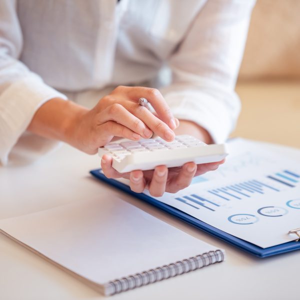A young woman's hand presses a calculator to determine and summarize the cost of mortgage home loans
