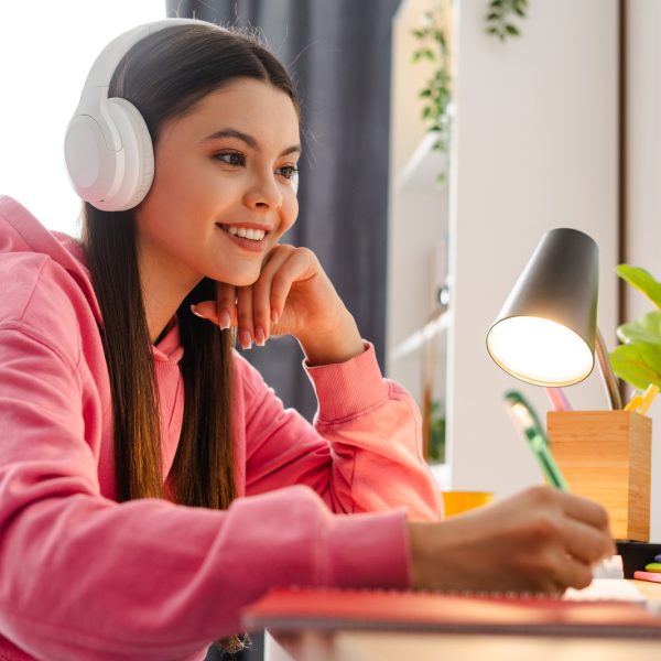 Young girl, teenager wearing headphones taking online course from home